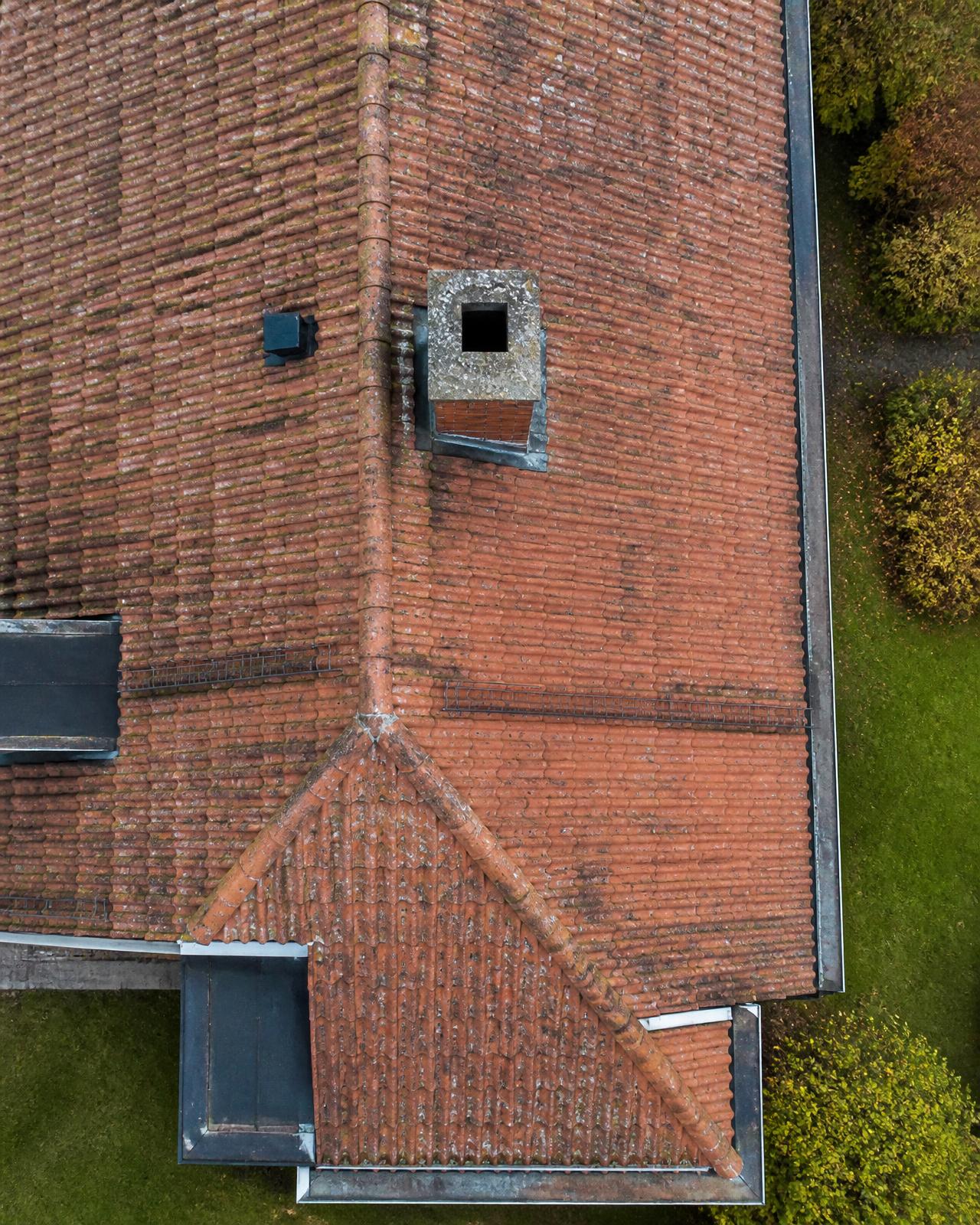 Drönarbild rakt ovanifrån på tegeltak med skorsten och hängrännor